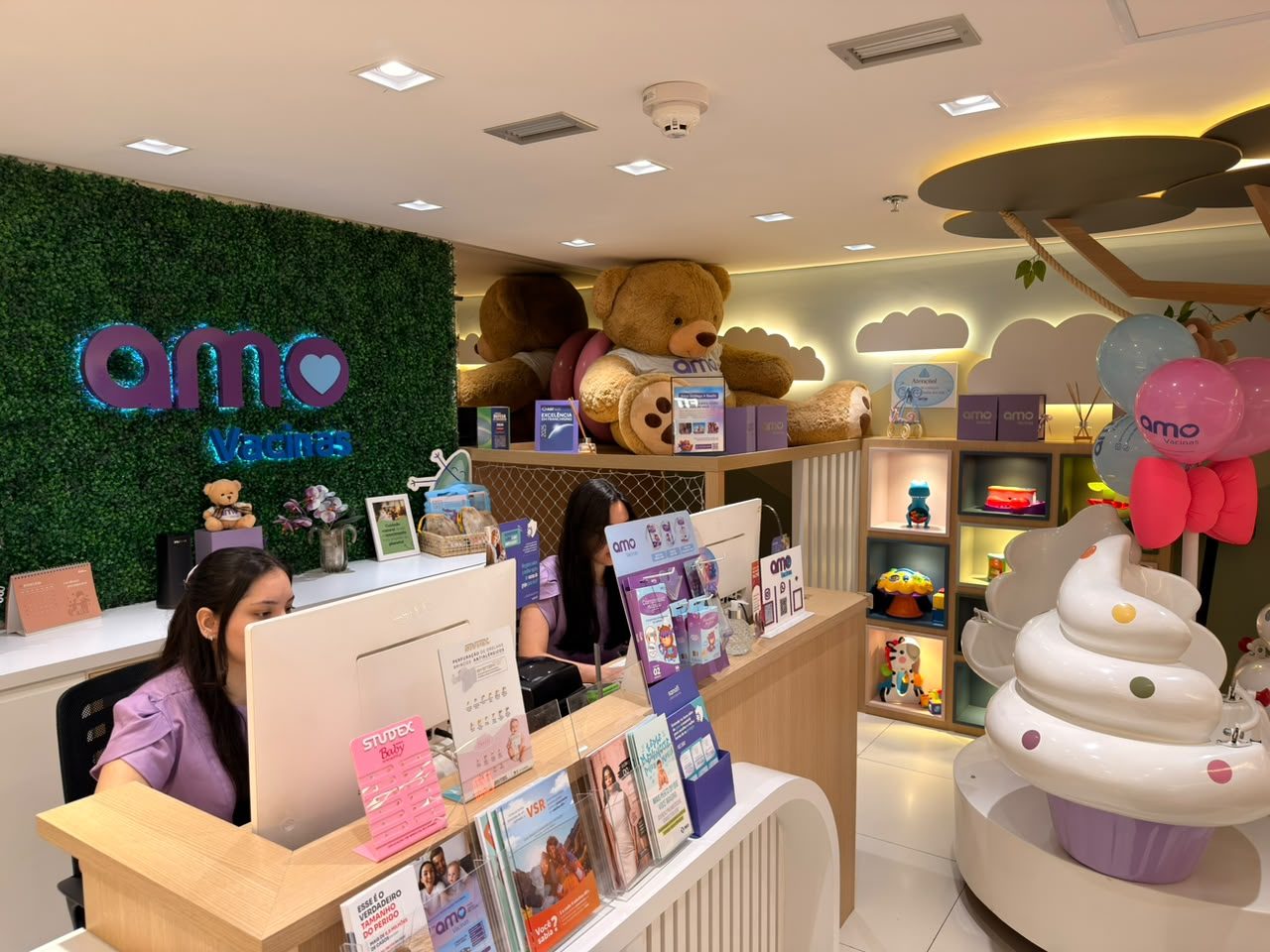 Recepção lúdica com muro verde, mascotes e atendimento acolhedor